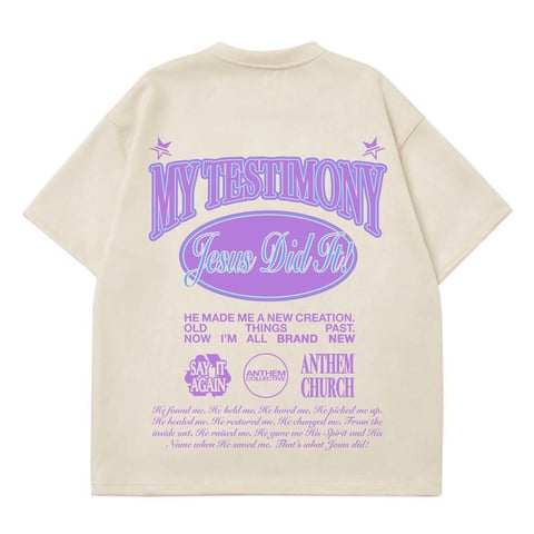 Cream-colored oversized t-shirt with purple graphic design featuring My Testimony Jesus Did It All text and religious motifs